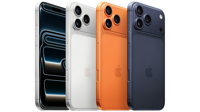 Fyra iPhone 17 Pro Max på rad visas i olika färger: svart med lysande skärm, vit, orange och mörkblå, alla med trippelkamerasystem.