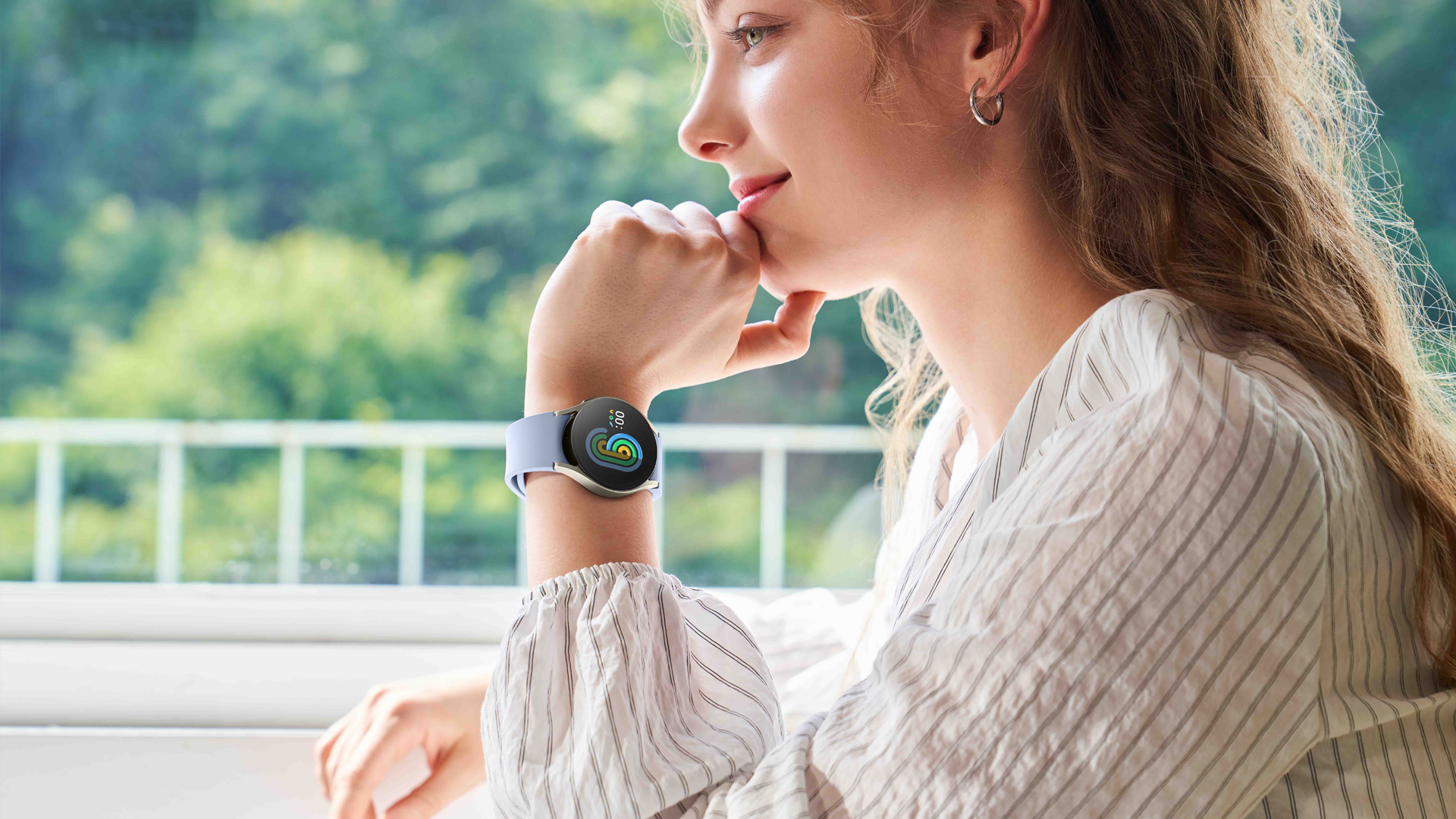 Kvinna sitter utomhus med Samsung Galaxy Watch6 på handleden.