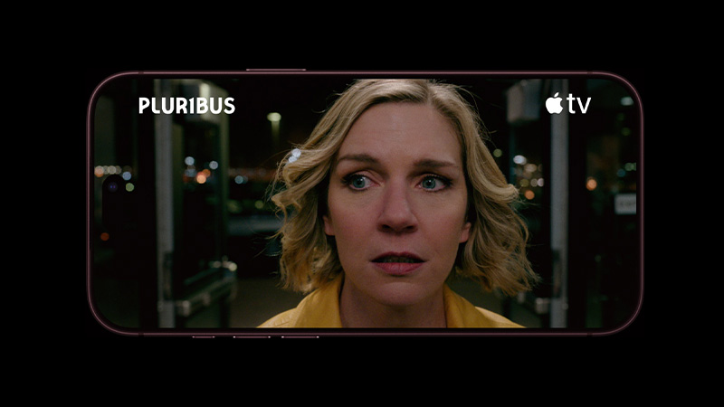 En iPhone visar en scen från Pluribus på Apple TV+, med en blond kvinna i gul jacka som ser förvånad ut på natten.