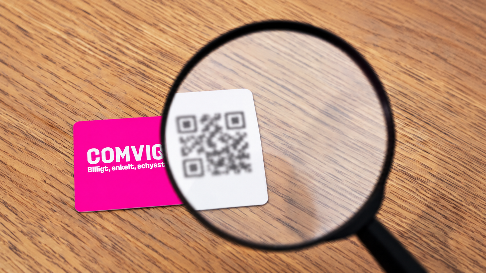 Förstoringsglas över en blurrad QR-kod för eSIM, bredvid ett rosa Comviq-kort.