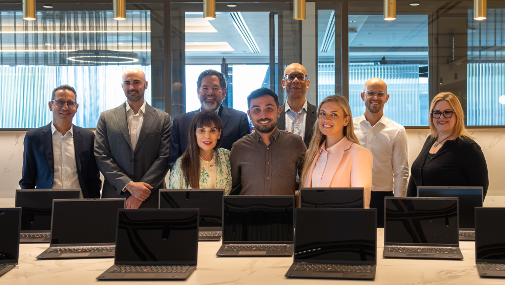 Donating 20 laptops to support Nacro’s learners A group of people standing in front of a table of open laptops