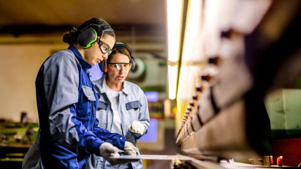 Building workforce Two women in protective gear working on machinery