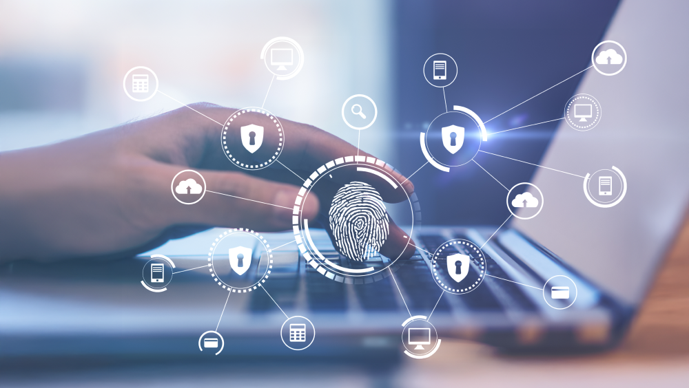 The New Security Perimeter A bubble map of a finger print connecting to locks, computers, phones, clouds and computers overlayed over an image of a person on a laptop.