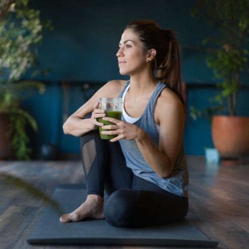 Woman drinking a green smoothie at a yoga studio