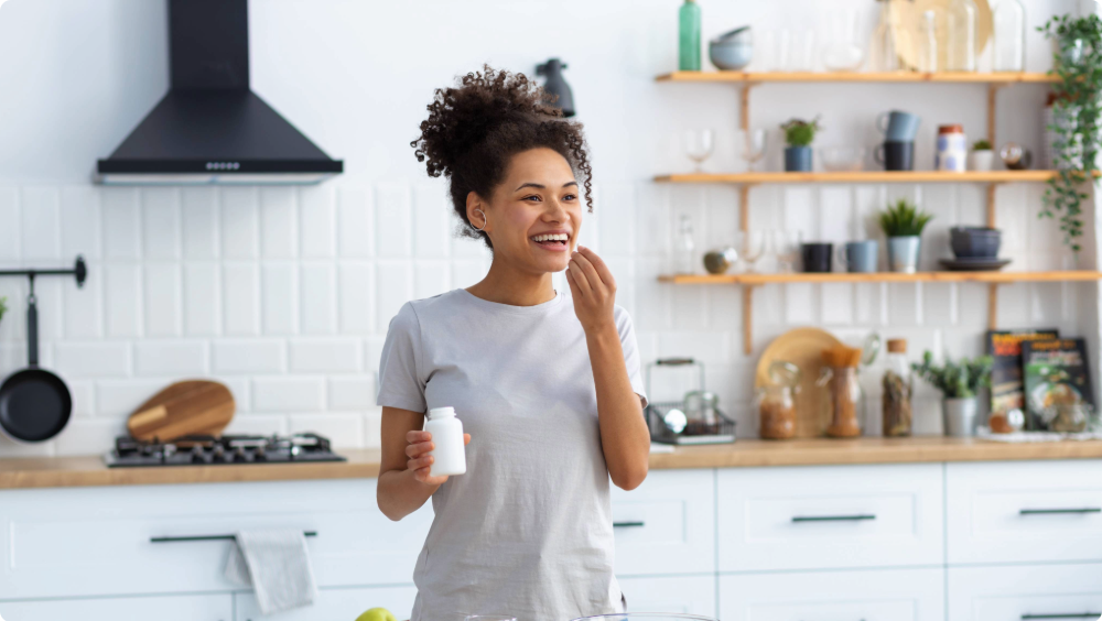 Women's Health A woman in a kitchen taking a vitamin