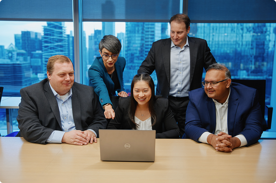 Five people sitting at a table around a laptop