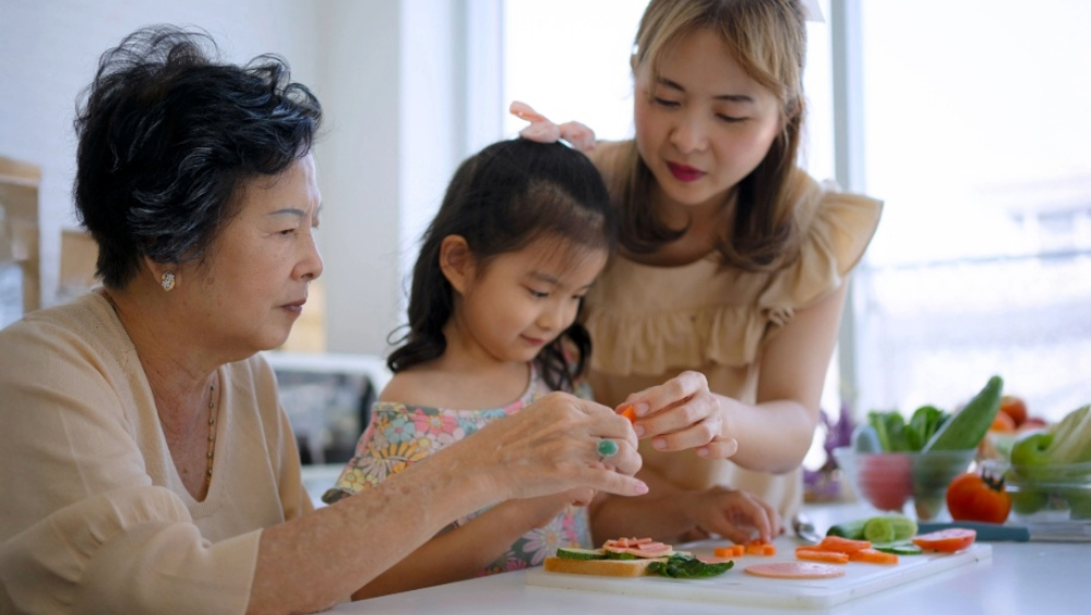 The sandwich generation A grandmother, mother and daughter making a sandwich