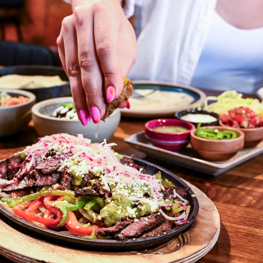 Woman squeezing lime onto Fajitas