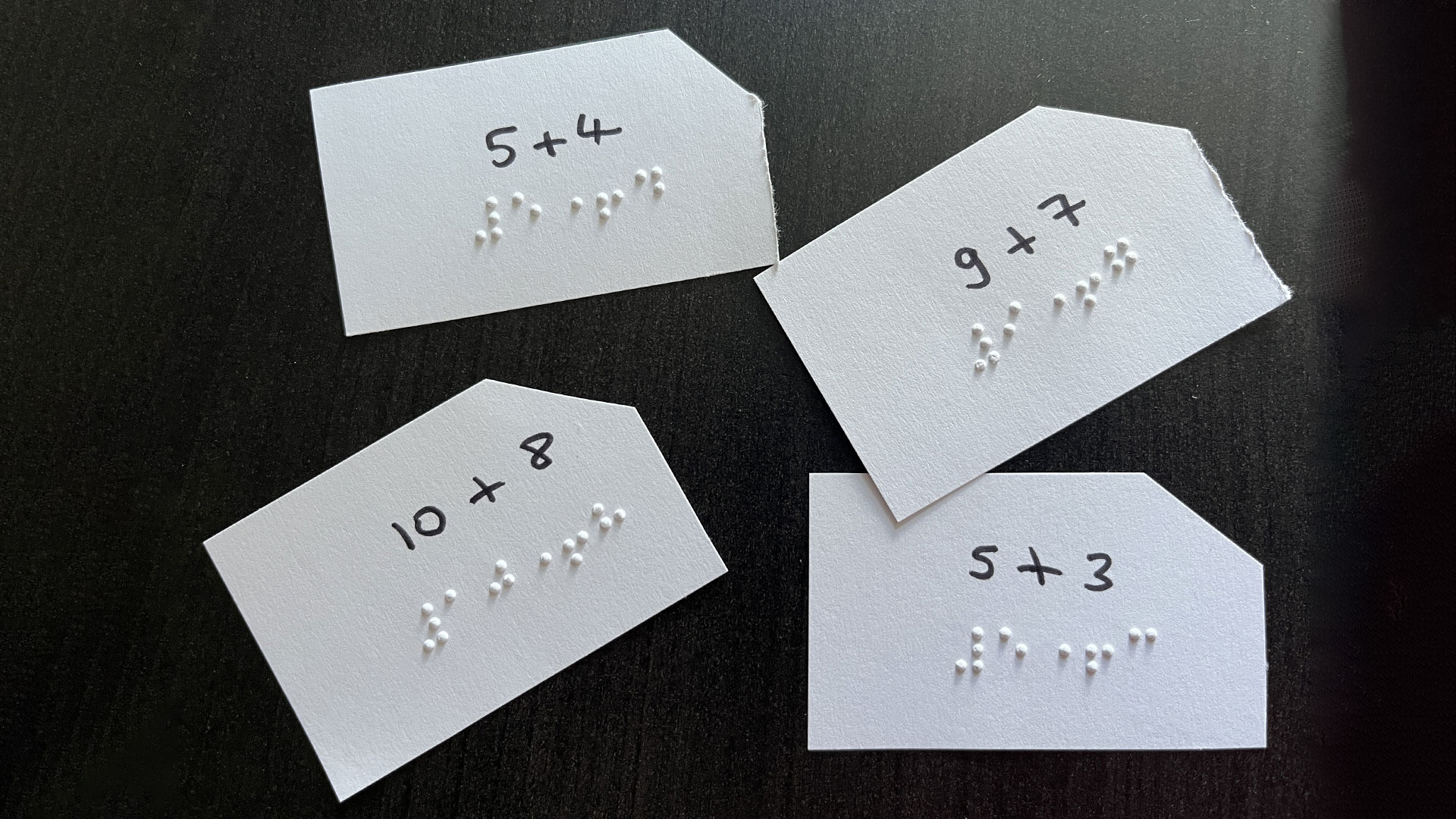 Addition is written in braille on cards and in black so that blind and sighted people can play together. The right corner of the label is cut off to make orientation easier.