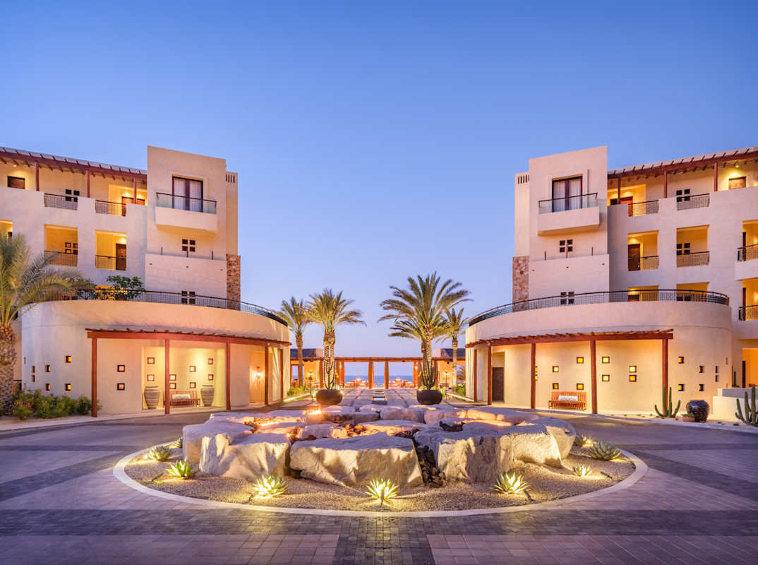 Grand entrance courtyard of Waldorf Astoria Los Cabos Pedregal, a luxury oceanfront resort in Baja California Sur, featuring palm-lined pathways, desert landscaping and elegant architecture