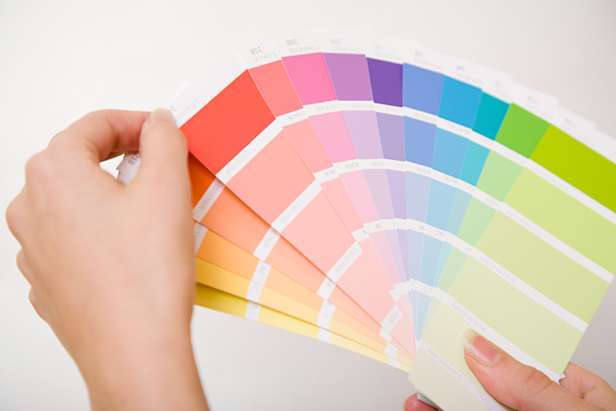 Image of a hand holding up some of the dulux colour swatches