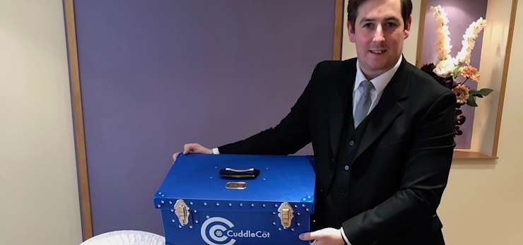 Funeral director holding a cuddle cot.