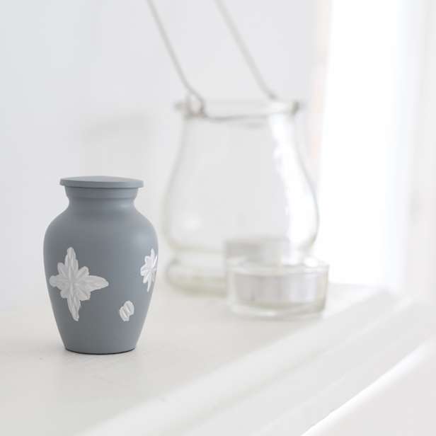 Grey urn with a white star decoration on a white mantelpiece
