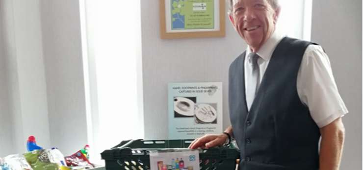 Funeral arranger, Andrew Bason, standing next to crates of food to be donated
