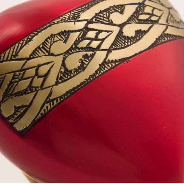 Close up image of the brass coloured band on a red urn
