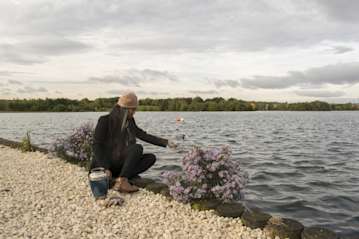 Woman scattering ashes next to a lake