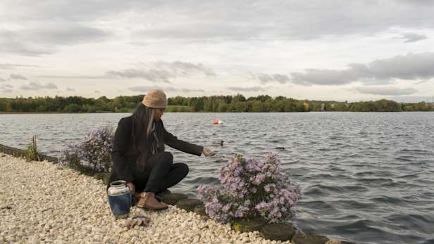 Woman scattering ashes next to a lake