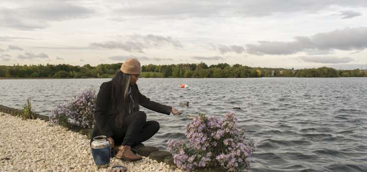 Woman scattering ashes next to a lake