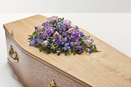 A combination of purple flowers on top of coffin