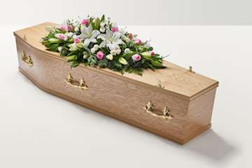 Zoomed out shot pink and white rose and lily floral display on top of coffin