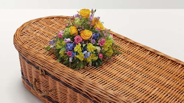 Brightly coloured rounded flower display on top of coffin