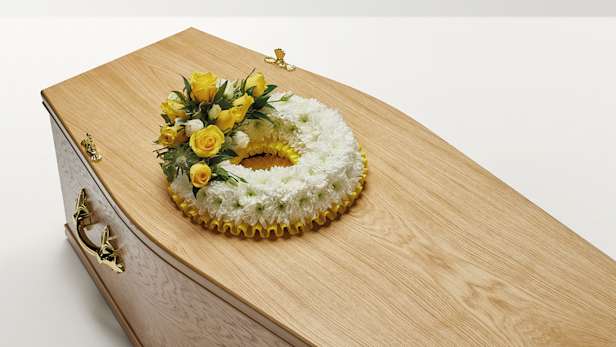 Yellow wreath of flowers on coffin
