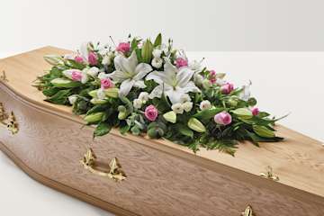 Pink and white rose and lily floral display on top of coffin