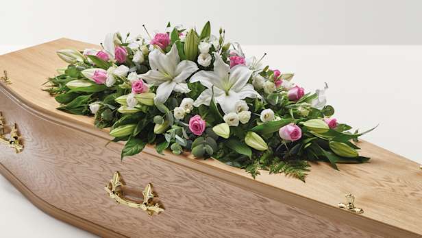 Pink and white rose and lily floral display on top of coffin