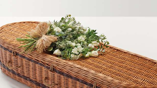 Large display of flowers with hand-tied bow on top of coffin