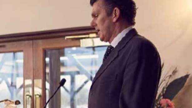 Man speaking at lectern at a funeral