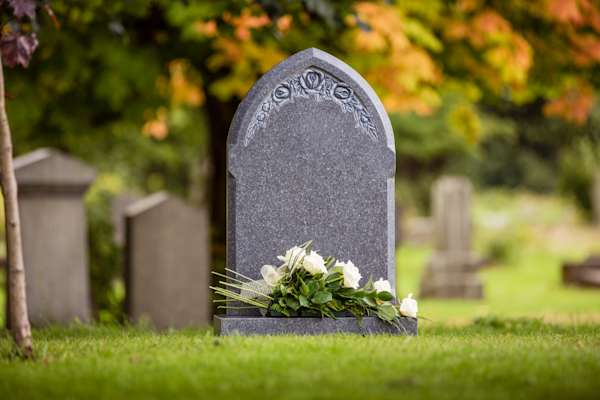 Grey natural headstone with white flowers laid.