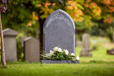 Grey natural headstone with white flowers laid.