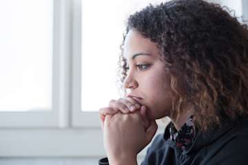 Finding balance in bereavement, woman with her hands clasped in front of her mouth.