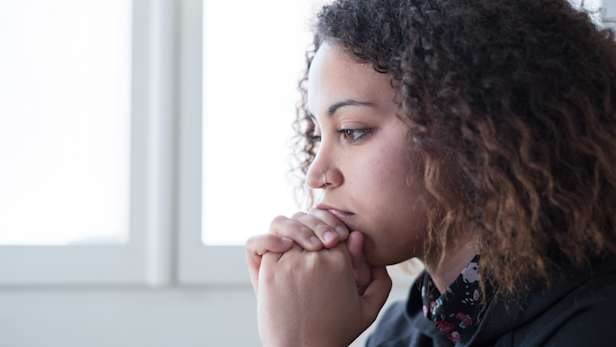 Finding balance in bereavement, woman with her hands clasped in front of her mouth.