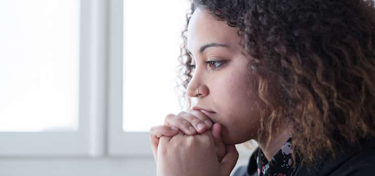 Finding balance in bereavement, woman with her hands clasped in front of her mouth.