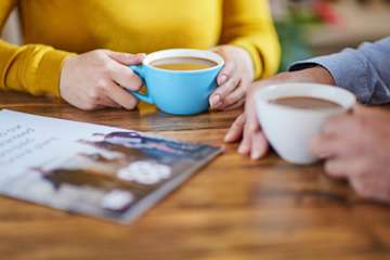 Couple sat at a table with cups of coffee discussing funeral plans.