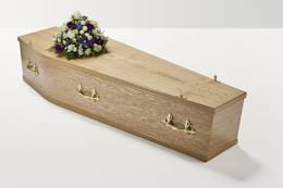 Zoomed out shot of white and purple flower display on top of coffin