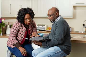 Couple sat in their kitchen discussing funeral plans.