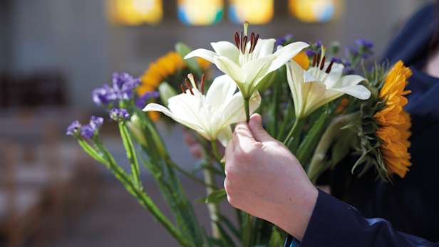 Funeral flower arrangement being held by a funeral director