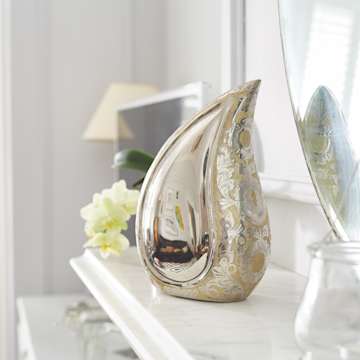 Silver coloured teardrop urn on a white mantelpiece