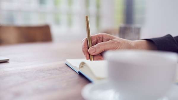 Person writing in a note book.