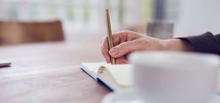 Person writing in a note book.