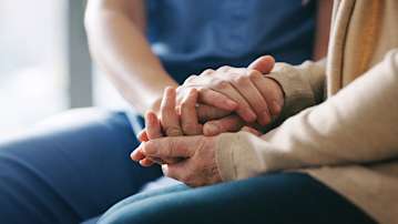 Two women holding hands, finding comfort.