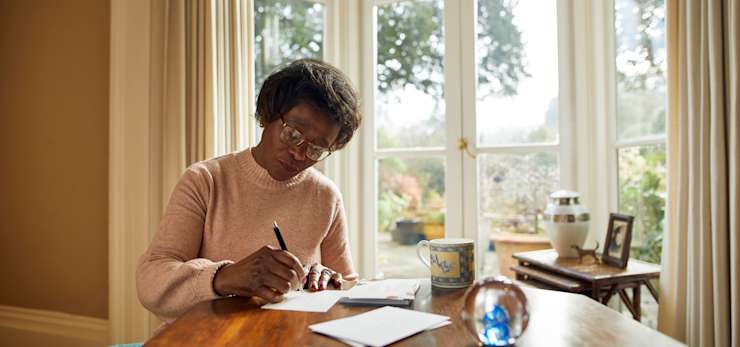Woman sat at a table writing on cards