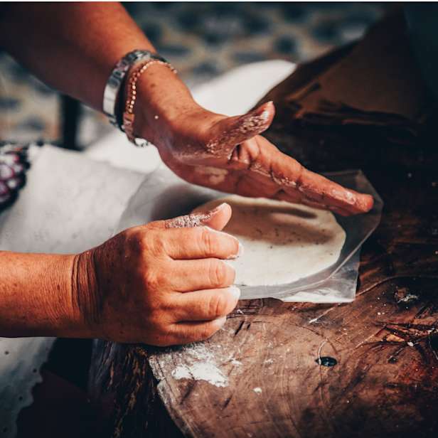 Hands working with clay on a wooden bench