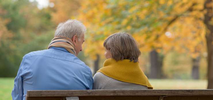 Couple sitting on a bench in a park.