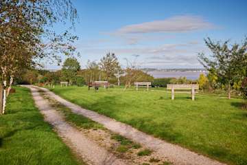 Natural woodland burial ground, with green fields and wooden park benches.