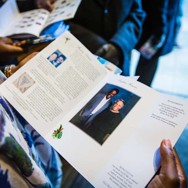 Hands holding a booklet open showing photographs and text