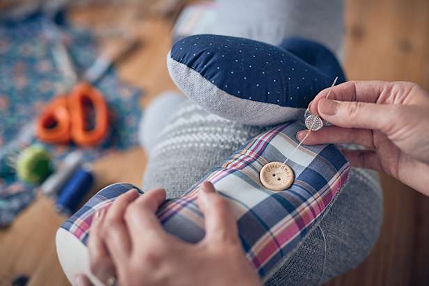 Sewing a button onto the memory bear