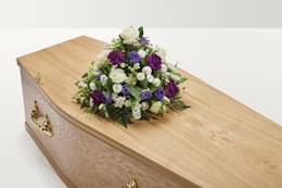 White and purple floral display on top of coffin